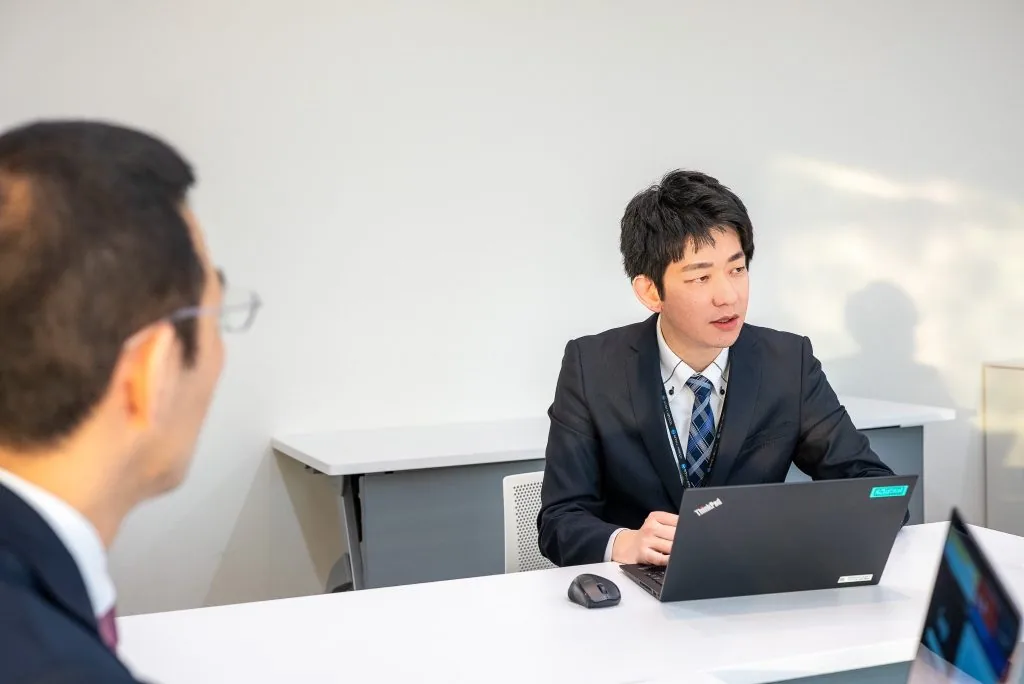 ノートPCを前に商談の状況を説明する担当者