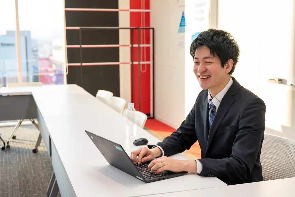 会議室でノートPCを開いて笑顔で話す担当者